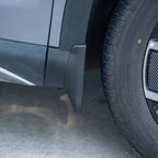 Close-up of a durable black plastic mudguard installed on a grey car body near the tire.