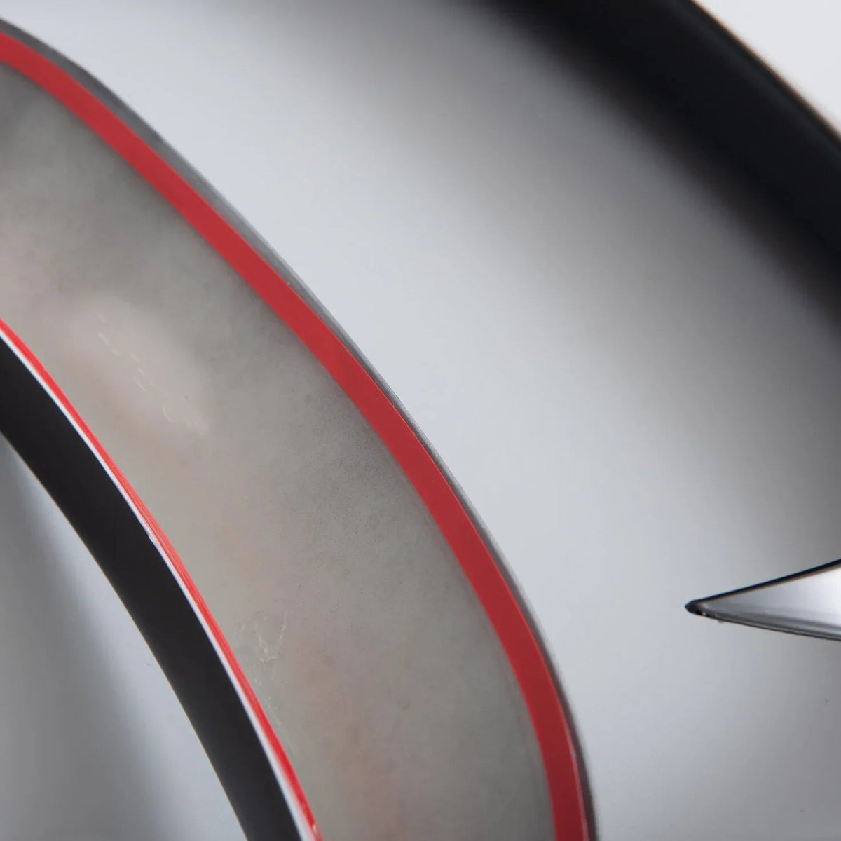 Close-up of a sleek car interior trim featuring a matte grey finish with a vibrant red accent line.