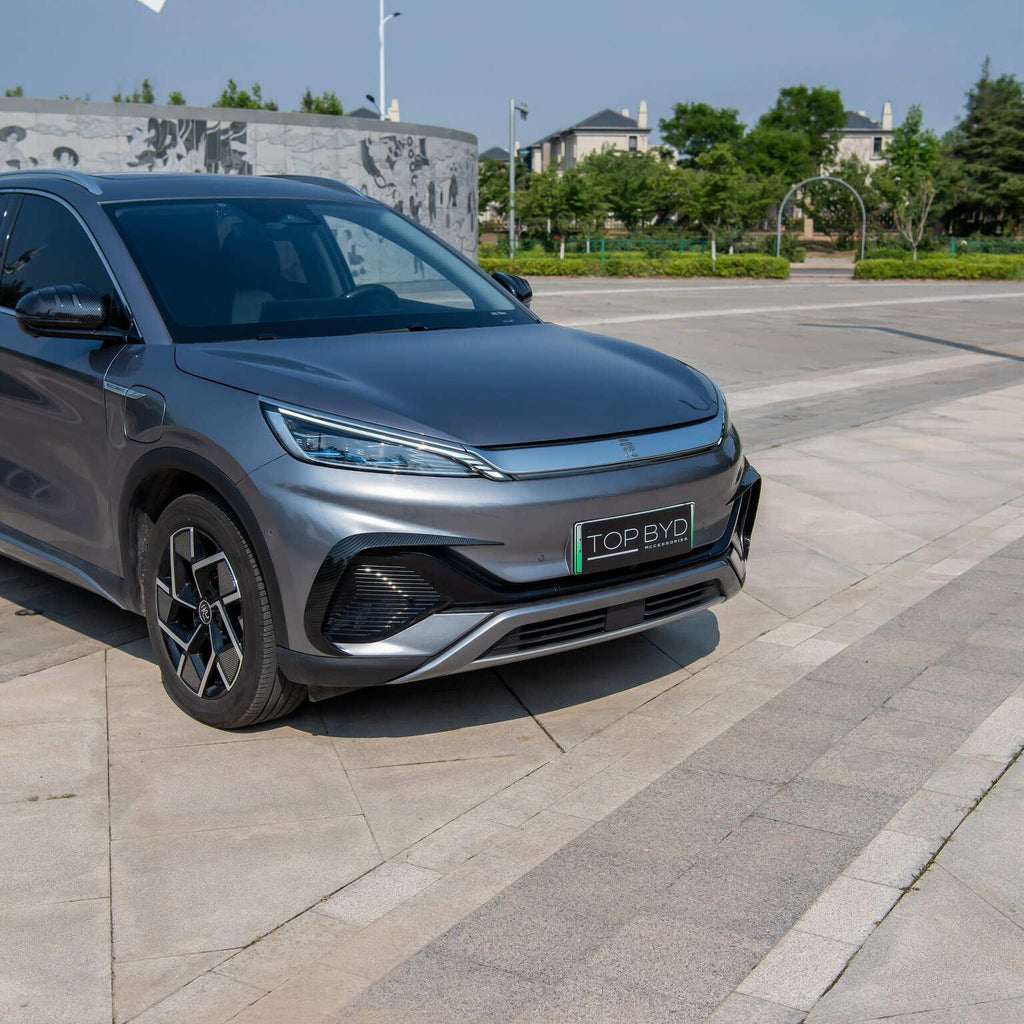 Front view of a sleek metallic grey BYD electric car parked on a light grey stone plaza.