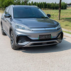 Front view of a sleek, metallic grey BYD electric car parked on a light-colored paved road.