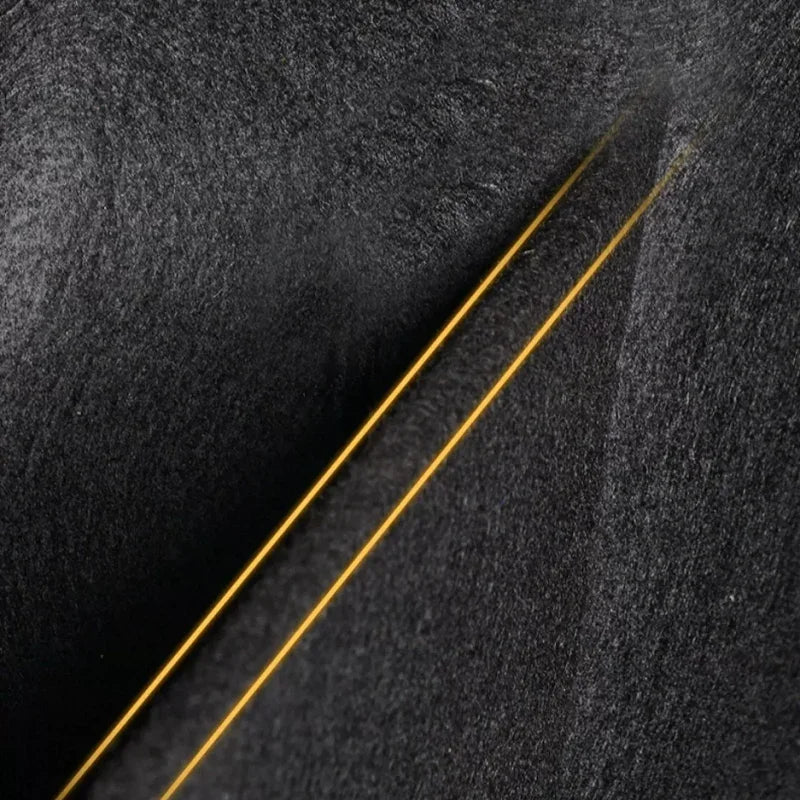Close-up of black textured car floor mat with elegant gold stitching detail.
