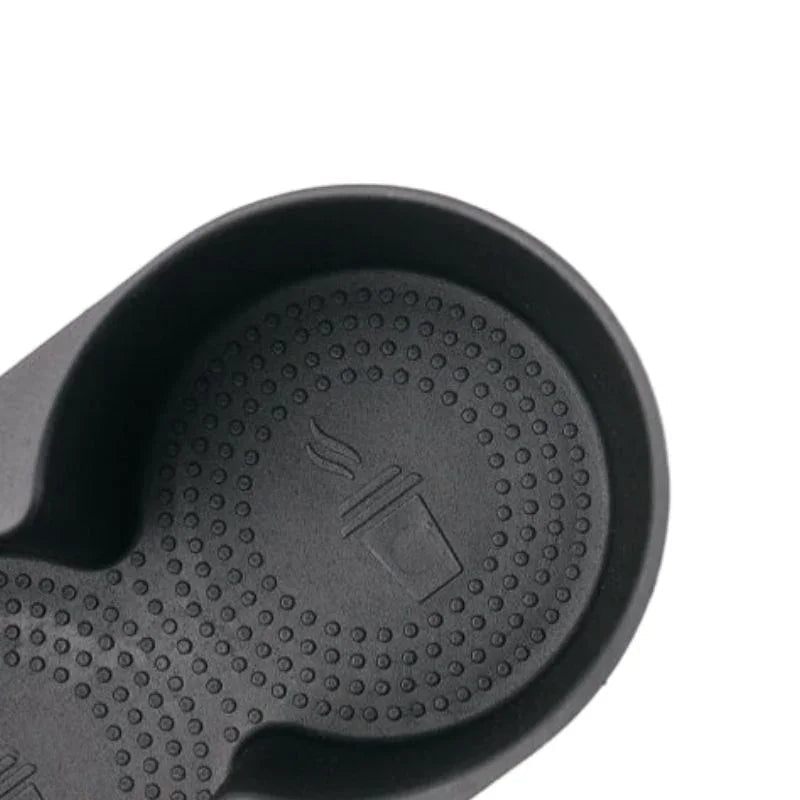 Close-up of a black textured rubber car cup holder mat with a drink icon.