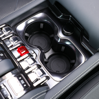 Close-up of a sleek black center console with dual cupholders and metallic trim buttons.
