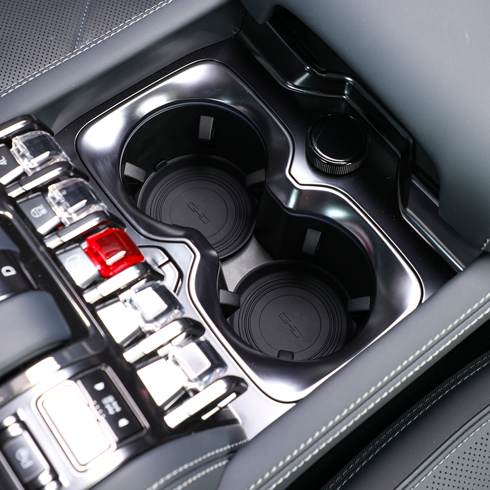 Close-up of a sleek black center console with dual cupholders and metallic trim buttons.
