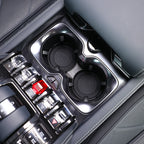 Close-up of a black gloss finish center console with dual cup holders and crystal-style buttons.