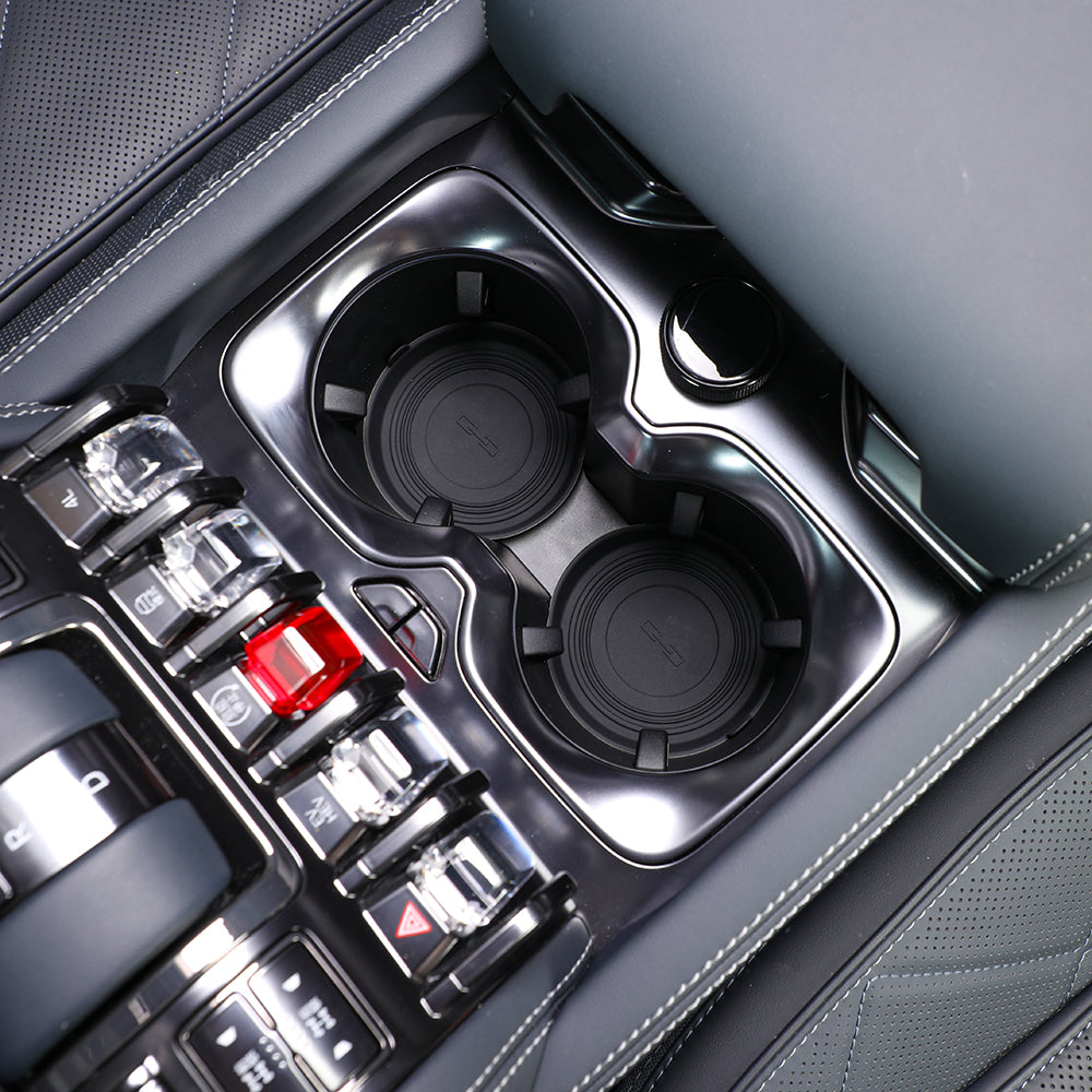 Close-up of a black gloss finish center console with dual cup holders and crystal-style buttons.