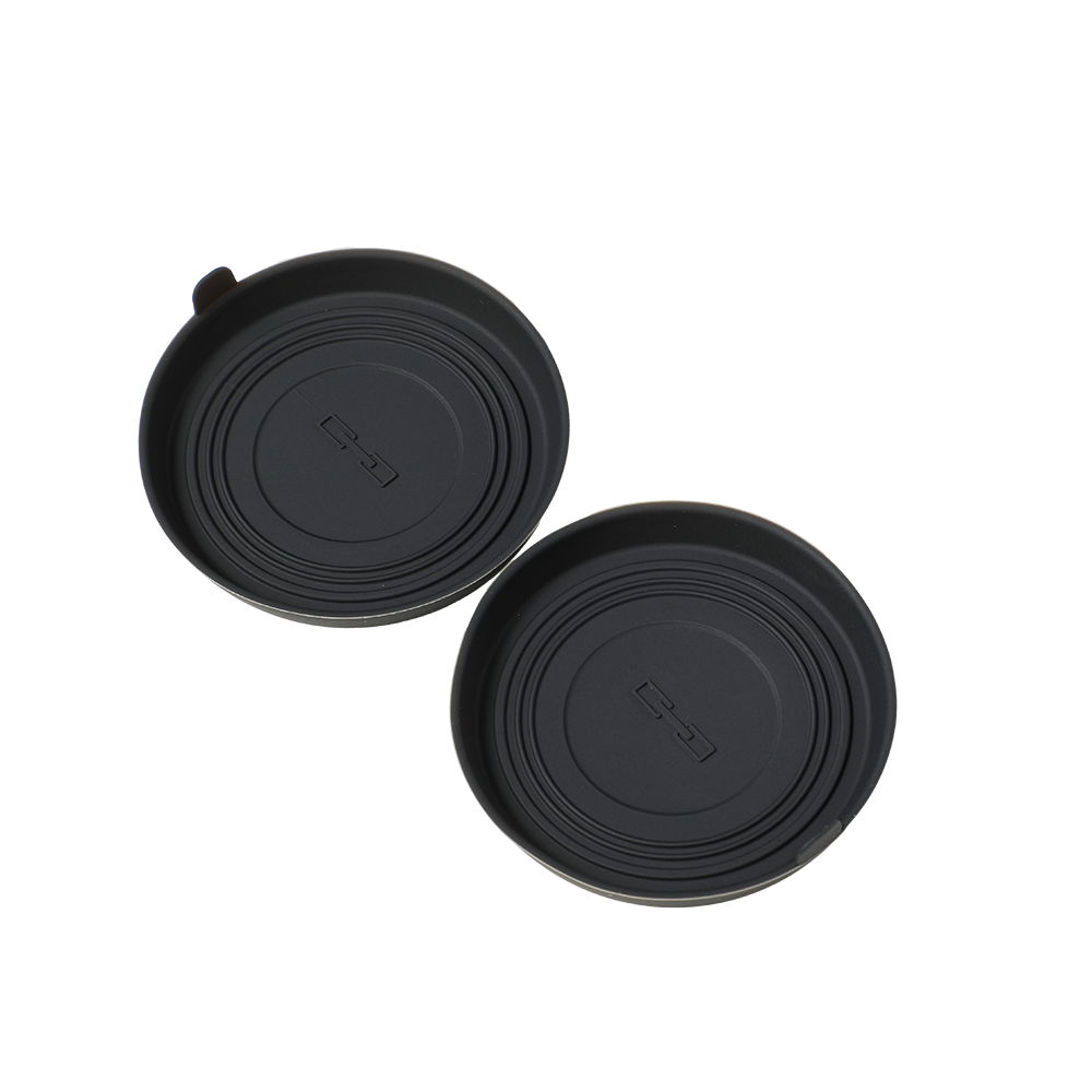 Two black matte silicone cup holder coasters with embossed logo for car interior protection.