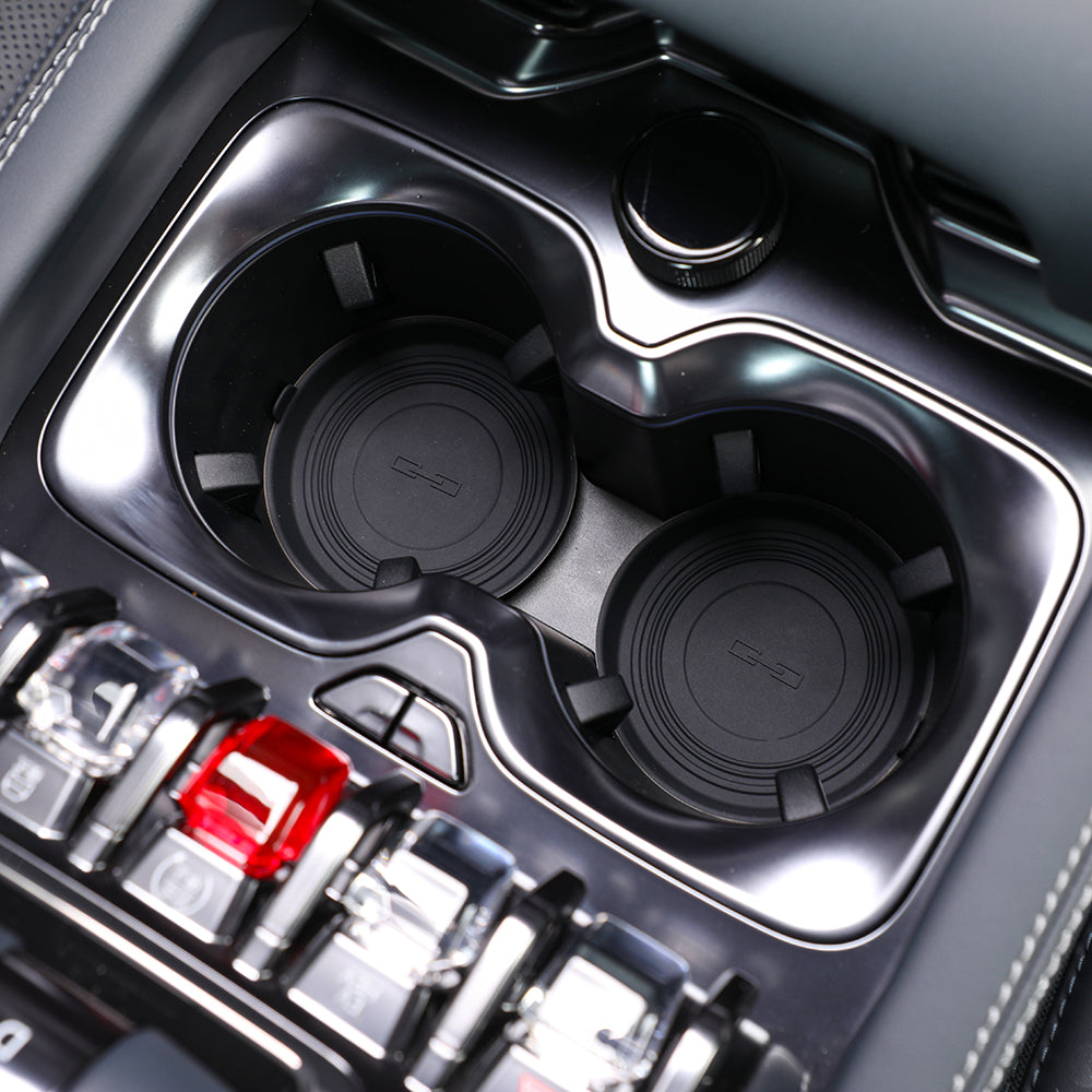 Close-up of sleek black gloss center console cup holders with textured rubber inserts.