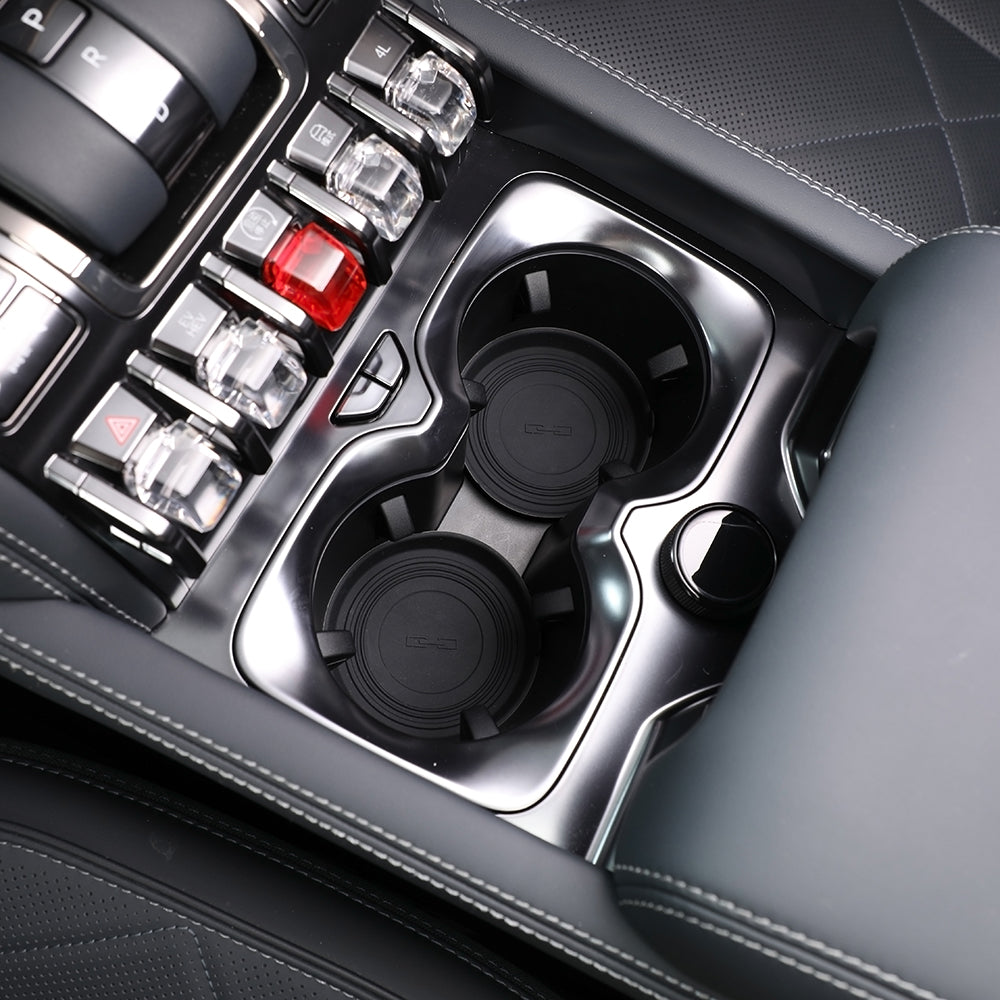 Close-up of black luxury car center console with dual cupholders and silver metallic trim.
