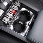 Close-up of black luxury car center console with dual cupholders and silver metallic trim.