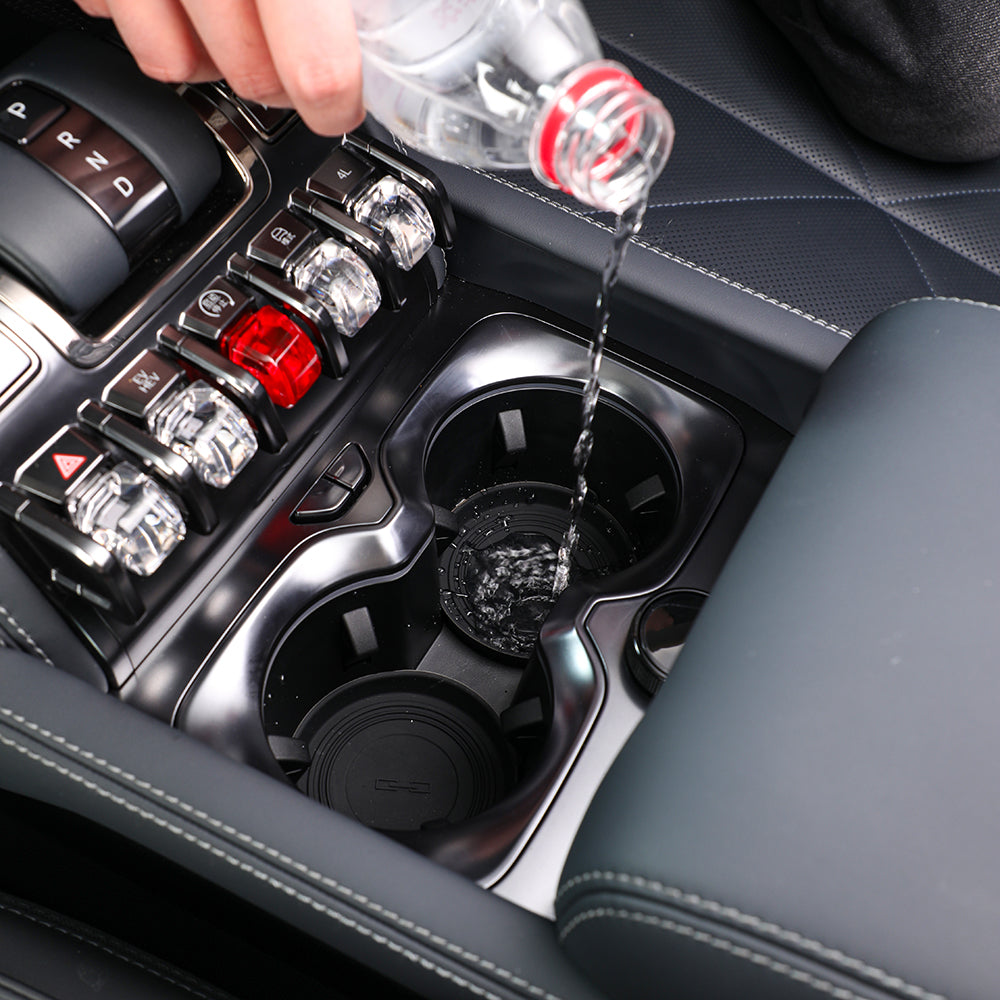 Water spilling into a black car cup holder liner designed for spill protection.