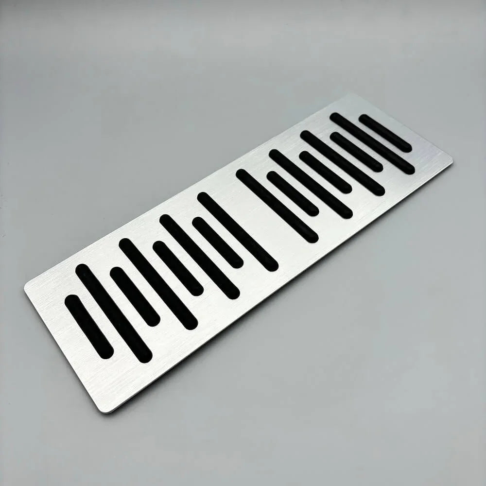 Silver brushed aluminum car accessory plate with decorative slotted cutouts.