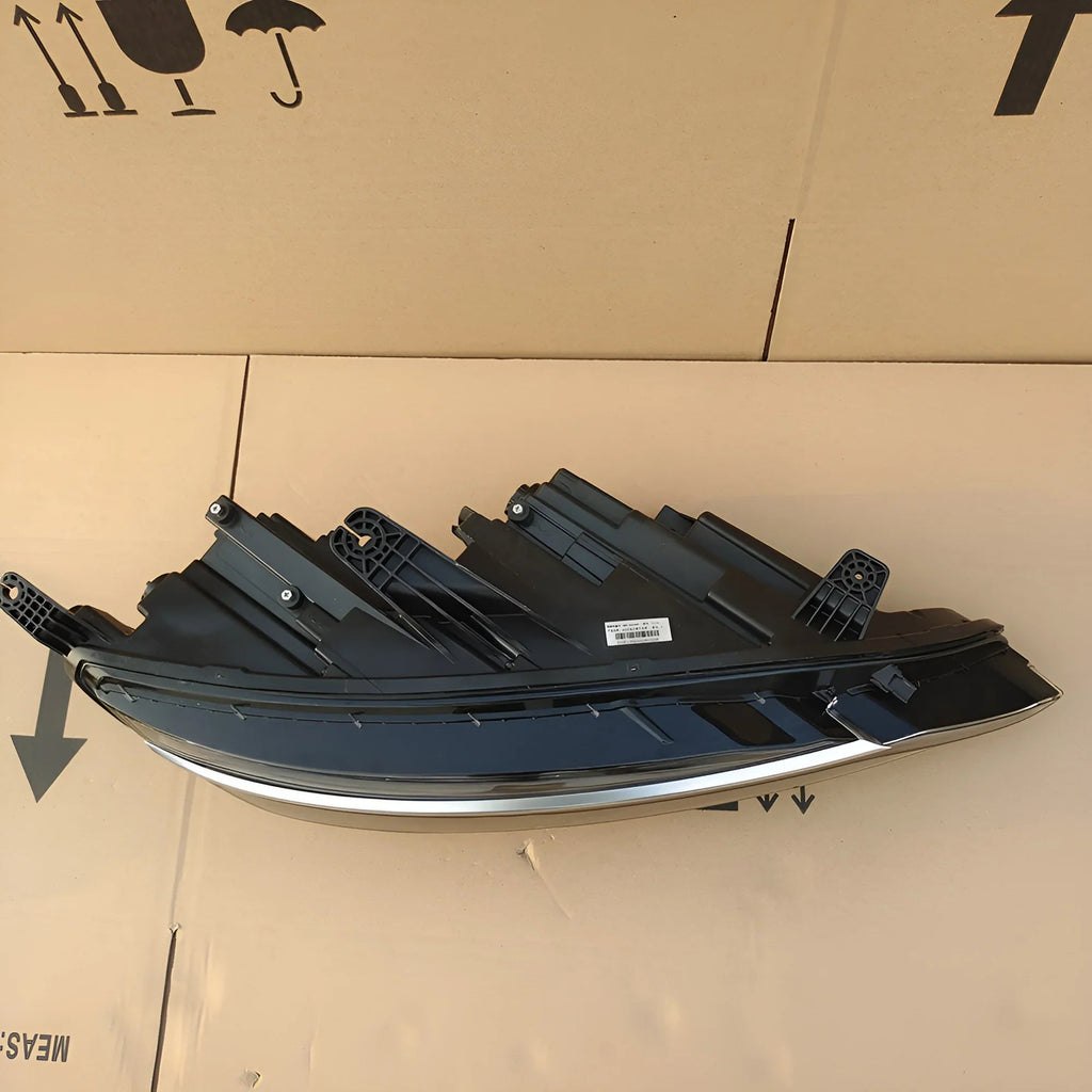 Sleek black automotive headlight assembly with chrome trim accents on a cardboard surface.