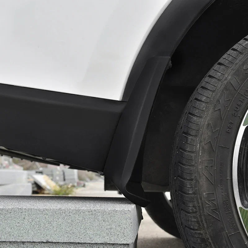 Close-up of a matte black durable plastic wheel arch fender flare installed on a white vehicle.