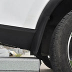 Close-up of a matte black durable plastic wheel arch fender flare installed on a white vehicle.