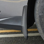 Close-up of a matte black durable plastic car mud flap installed behind a vehicle wheel.