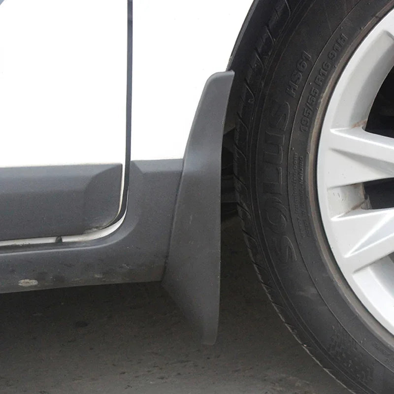 Close-up of a durable matte black plastic mud guard installed behind a car tire.