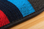 Close-up of durable woven fabric with red, navy, and bright blue stripes and black stitched edge.