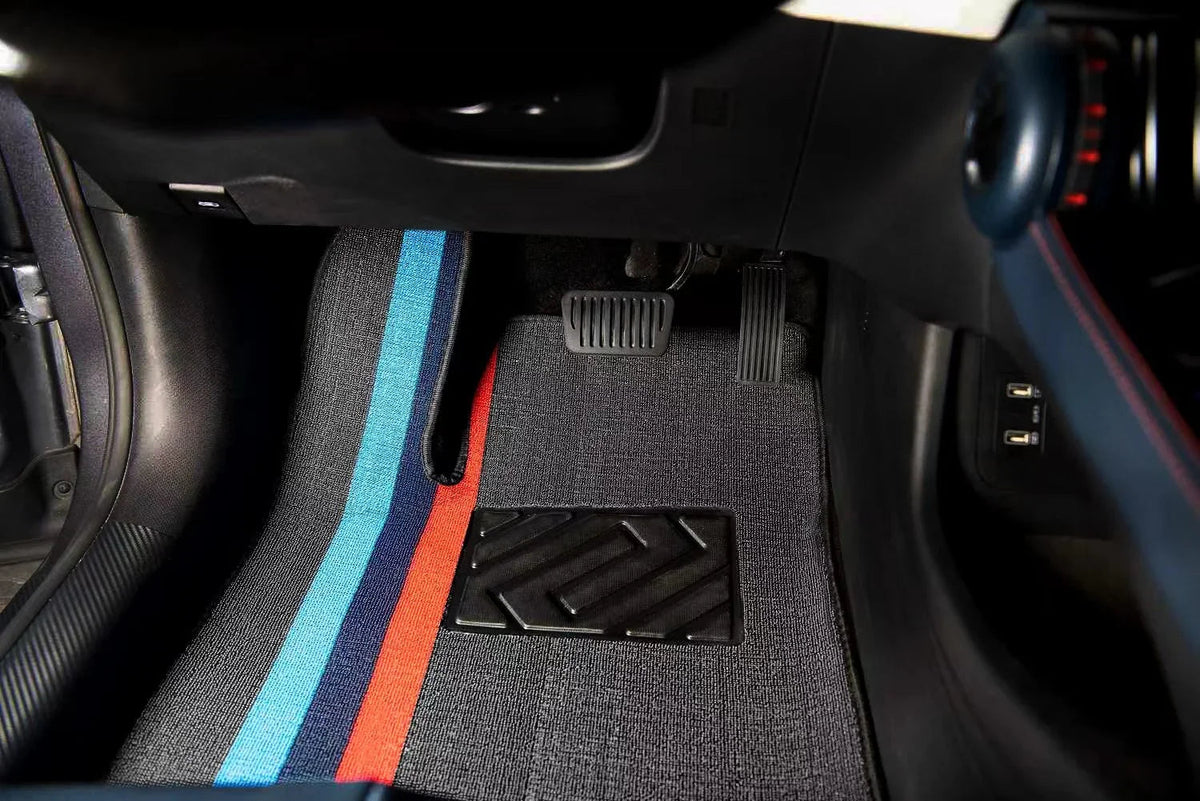 Grey fabric car floor mats featuring distinctive blue and red racing stripes.