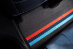 Custom dark grey fabric car floor mat featuring vibrant red and blue racing stripes.