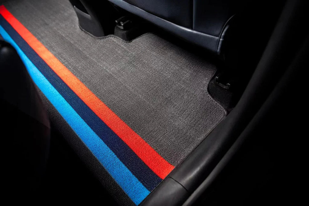 Custom grey car floor mat with distinctive blue and red racing stripes.