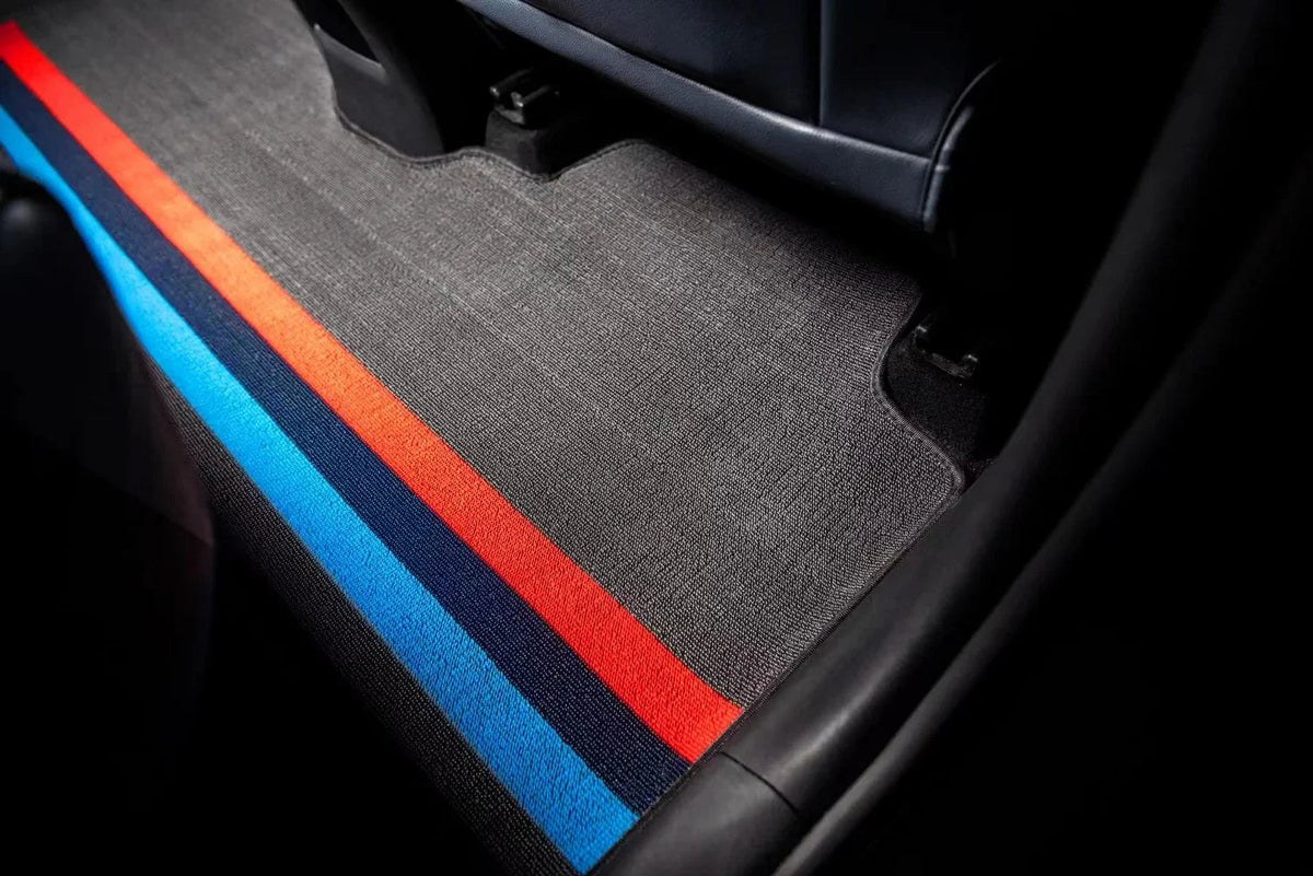Custom grey car floor mat with distinctive blue and red racing stripes.