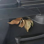 Dry brown leaves trapped in the crevices of a dark grey car interior dashboard.