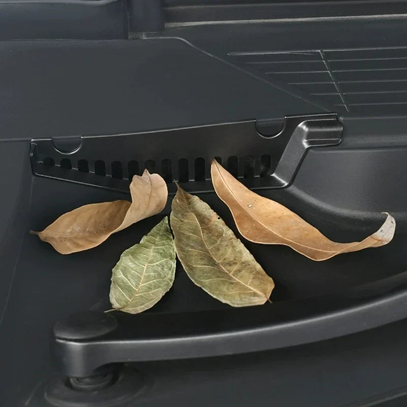 Black matte durable plastic door pocket organizer holding dried leaves in a car interior.