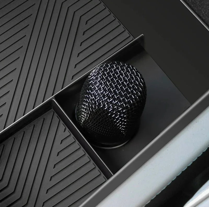 Close-up of a black textured carbon fiber gear shift knob in a car interior