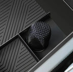 Close-up of a black textured carbon fiber gear shift knob in a car interior