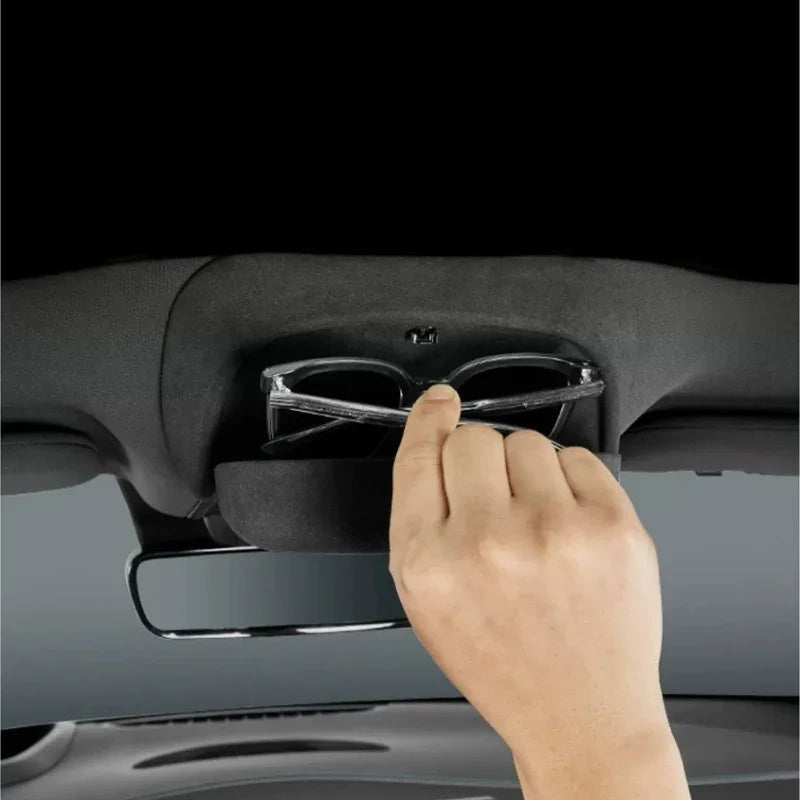 Hand retrieving black sunglasses from a grey fabric overhead car console organizer.