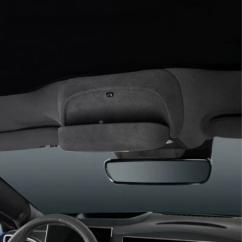 Black fabric car interior sun visor and rearview mirror against a dark ceiling.