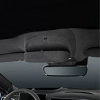 Black fabric car interior sun visor and rearview mirror against a dark ceiling.
