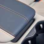 Premium navy blue leather center console armrest with contrasting orange stitching.