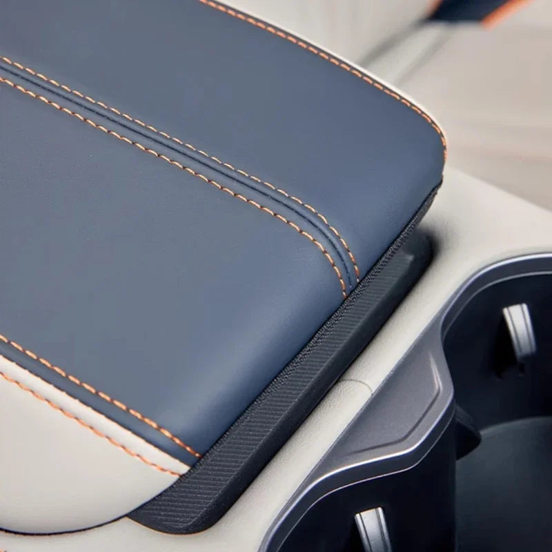 Premium navy blue leather center console armrest with contrasting orange stitching.