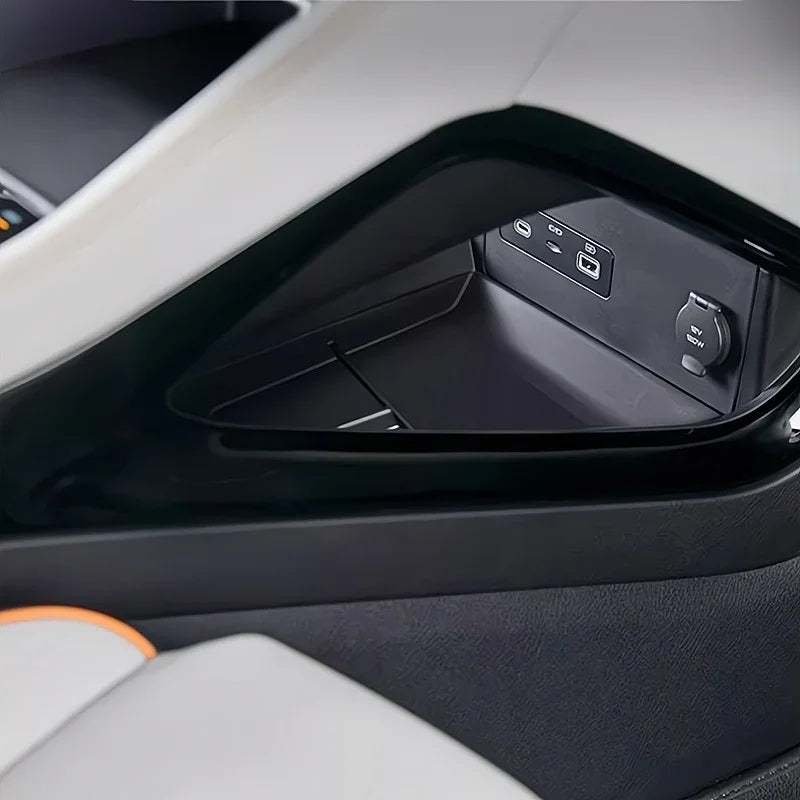 Close-up of a black sleek car center console storage tray with USB ports and EV power outlet.