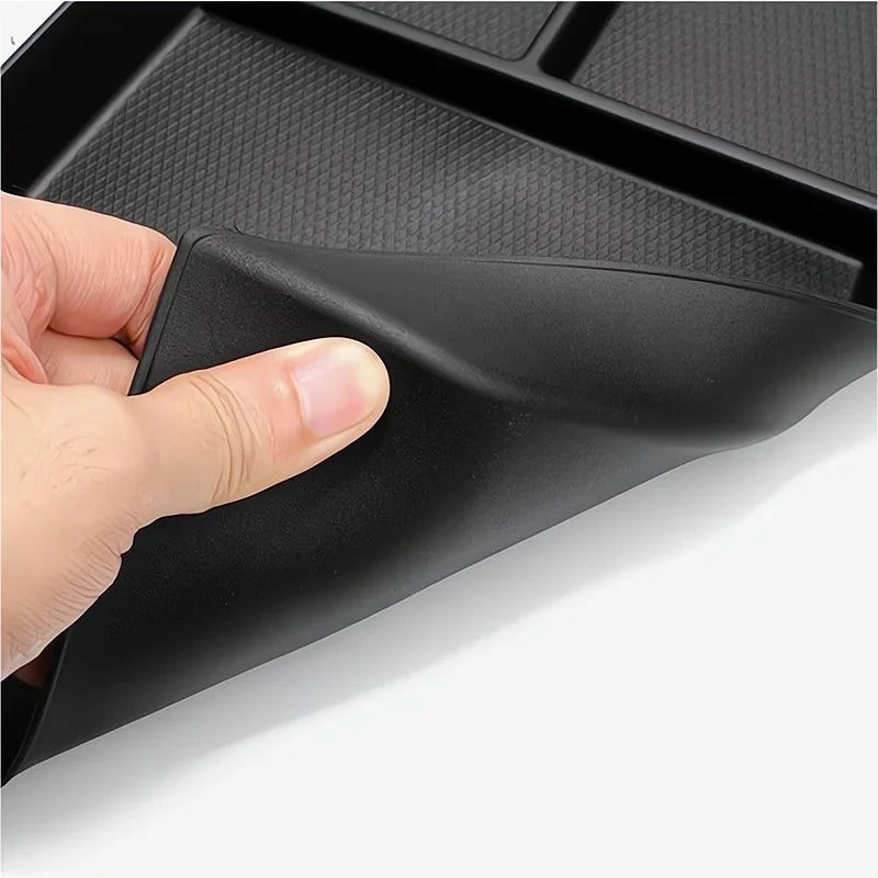Close-up of a flexible, black textured rubber car floor mat demonstrating its durable material.