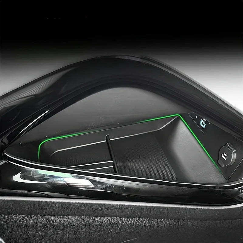 Black glossy center console storage tray with vibrant green ambient lighting for BYD cars.