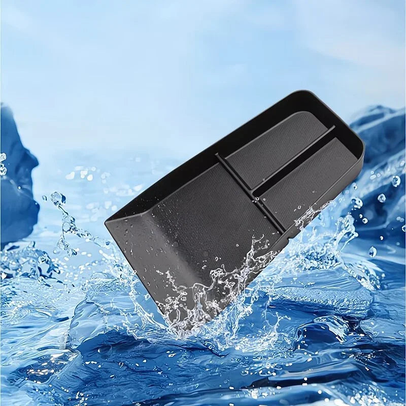 Water-resistant black plastic car organizer tray with compartments splashing in water.