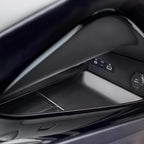 Close-up of a black glossy interior car storage compartment with a 12V power outlet.