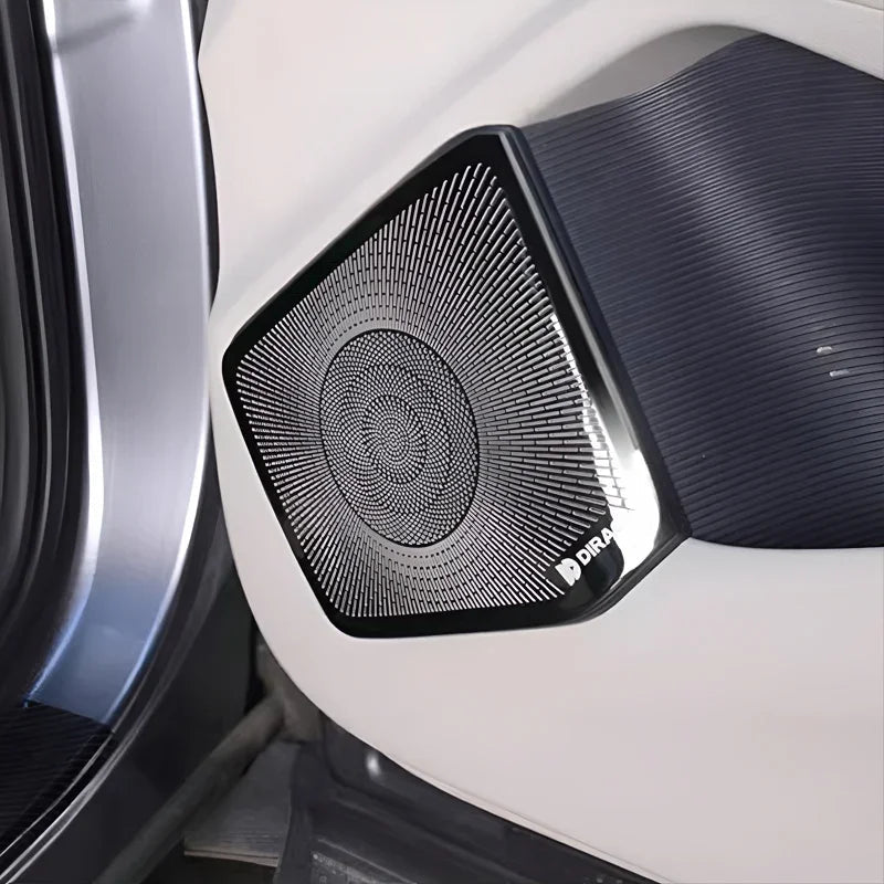 Black Dirac premium speaker grille with a textured radial pattern on a white car door panel.