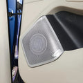 Silver metallic Dirac speaker grille with a textured pattern on a black car door panel.