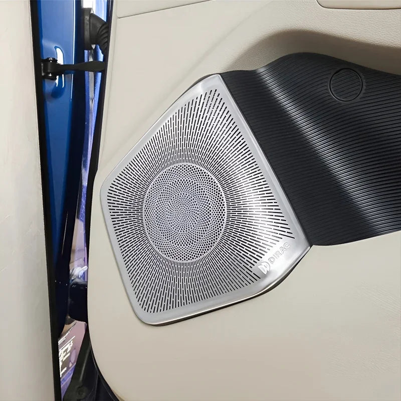 Silver metallic Dirac speaker grille with a textured pattern on a black car door panel.