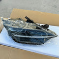 Sleek black aftermarket car headlight assembly wrapped in protective clear plastic.