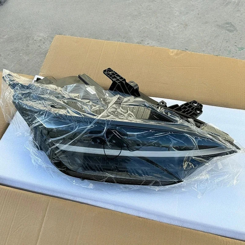 Sleek black aftermarket car headlight assembly wrapped in protective clear plastic.