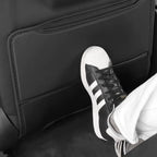 Close-up of a foot resting on a premium black leather car kick protector mat.