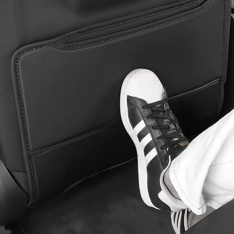 Close-up of a foot resting on a premium black leather car kick protector mat.