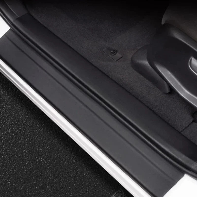 Black matte-finish protective door sill guard installed on a vehicle threshold.