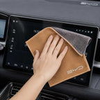 Person cleaning a car's touchscreen display with a BYD branded towel.