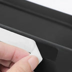 Peeling off white adhesive backing from a black matte car floor mat accessory.